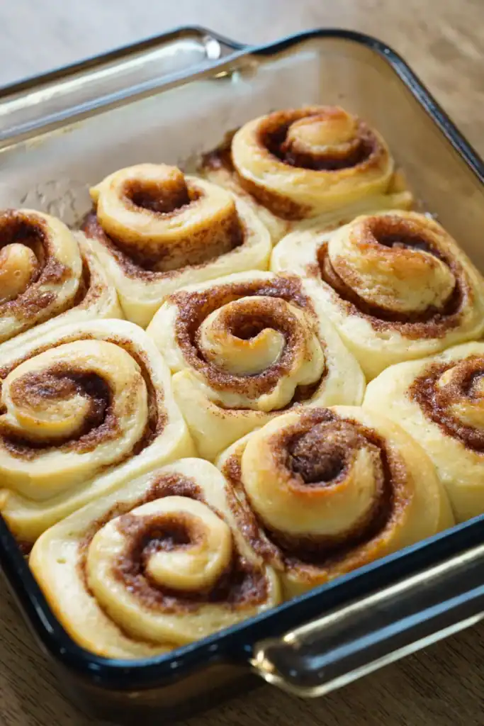 nine cinnamon rolls in a glass baking pan without icing.