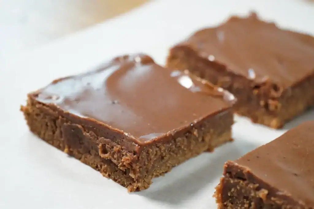 3 squares of brownies laying on a white surface.